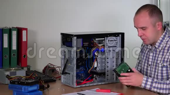 年轻的维修工在电脑中心将硬盘安装到台式电脑机箱中视频的预览图