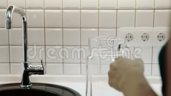 女人从家里厨房的金属水龙头里装满里的饮用水视频的预览图