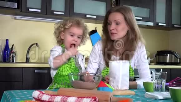 小女孩妈妈帮手尝巧克力蛋糕粉用勺子搅拌视频的预览图