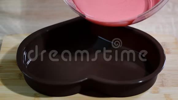 将粉红色的慕斯倒入心形模具中在厨房做慕斯蛋糕的糖果商视频的预览图