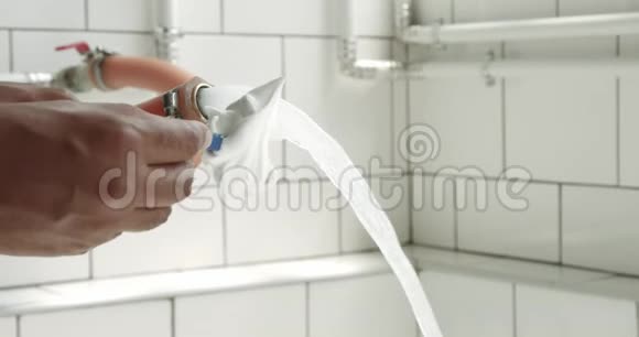 男人在阳光明媚的浴室里用水洗剃须刀视频的预览图