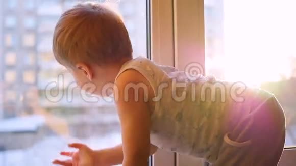 一个孩子用缓慢的动作透过阳光望着窗外视频的预览图