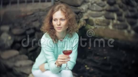 一个女人坐在后墙上一杯酒和一杯酒视频的预览图