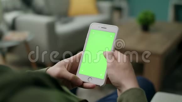 男手在客厅里用绿色屏幕的手机视频的预览图
