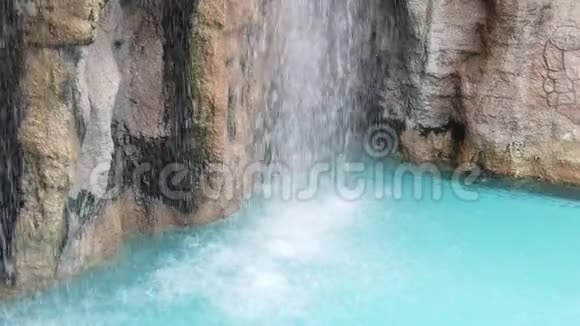 酒店温泉度假村的泳池边瀑布溅到岩石上视频的预览图