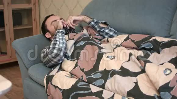 假装得流感的年轻人躺在沙发上视频的预览图