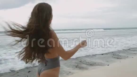 自由而快乐的女孩穿着泳装沿着白沙奔跑视频的预览图
