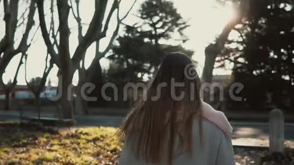 美丽的年轻女子在明媚的秋天在公园散步女人转身对着镜头微笑享受阳光视频的预览图