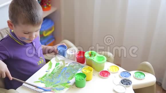 美丽的孩子坐在桌子上画着彩色颜料视频的预览图