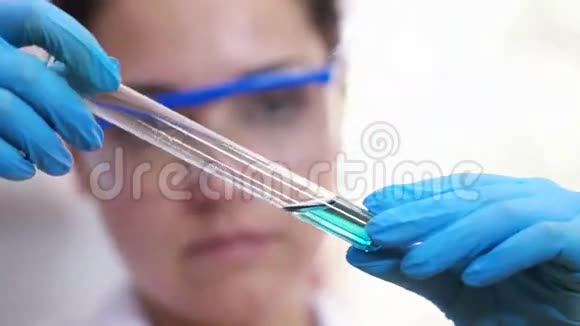 带眼镜和乳胶手套的女性医学或科学研究者或女性医生看透明溶液试管视频的预览图
