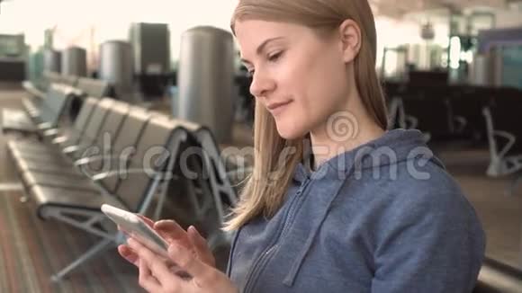 美丽的女人在机场使用智能手机浏览互联网和她的朋友交流视频的预览图