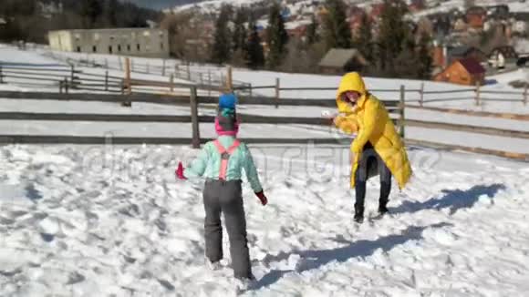 活跃的家庭在乡村度假期间享受阳光般温暖的天气妈妈正在玩雪球视频的预览图