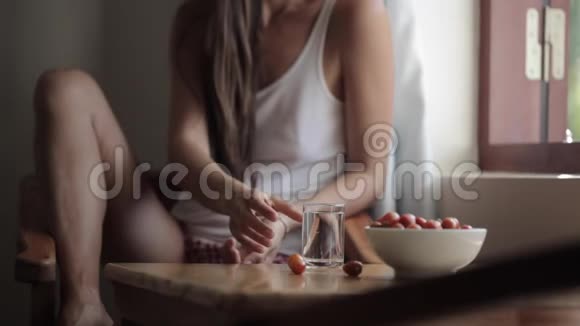 年轻女子坐在桌边喝水的歪歪扭扭的形象视频的预览图