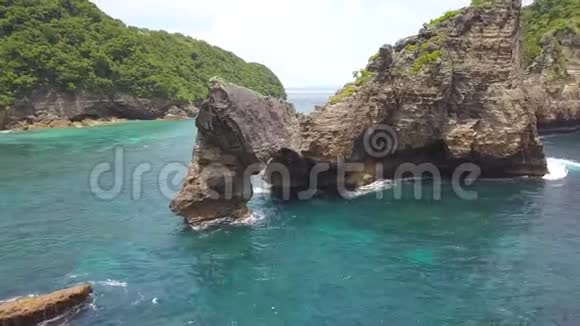 空中飞行在印度尼西亚努沙佩尼达的阿图海滩绕着神奇的悬崖岩拱岛飞行4K视频的预览图