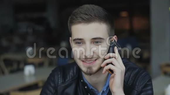 年轻的帅哥在4K咖啡馆的智能手机上聊天视频的预览图