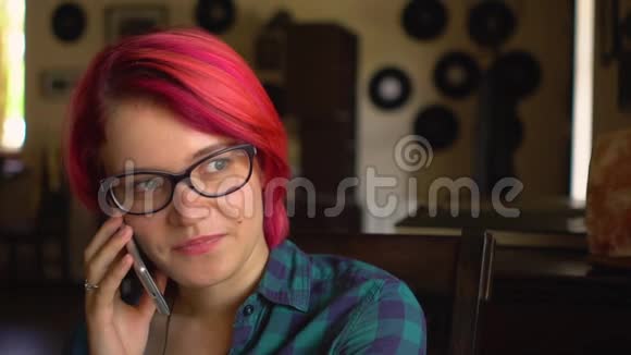 身着时髦眼镜戴着智能手机在咖啡馆里谈笑风生的金发美女视频的预览图