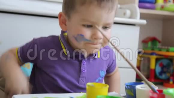 一个孩子坐在桌子上画彩色颜料视频的预览图
