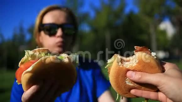 一男一女在草坪上吃快餐他们互相咬掉汉堡包在一个视频的预览图
