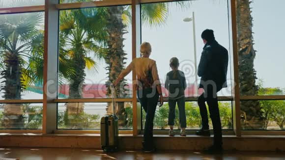 我们一起旅行家人在机场候机楼看看飞机附近有一个旅行袋轮子手掌视频的预览图