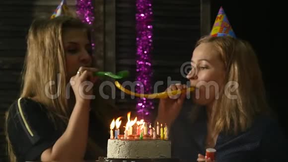 两个喜怒无常的女人吹灭了生日蛋糕上的蜡烛蜡烛熄灭了慢动作视频的预览图