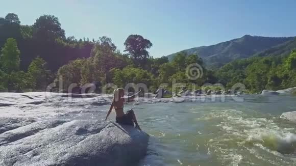 江水照热带景观石上少女小憩视频的预览图
