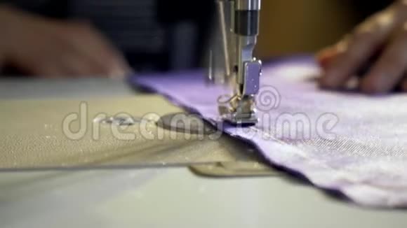 一个女人在缝纫机上用白线缝一块紫色布视频的预览图