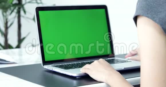 亚洲女性办公室雇员在她的桌面工作在一个模拟绿色屏幕笔记本电脑在肩膀上视频的预览图