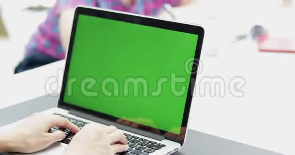 亚洲女性办公室雇员在她的桌面工作在一个模拟绿色屏幕笔记本电脑视频的预览图