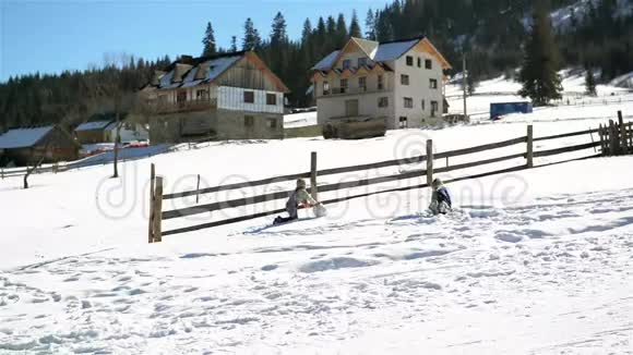 女孩和男孩在山上滚动一个巨大的雪球在温暖的阳光日在山的农村儿童视频的预览图