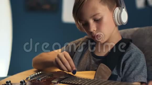 带吉他学耳机歌曲的男孩视频的预览图