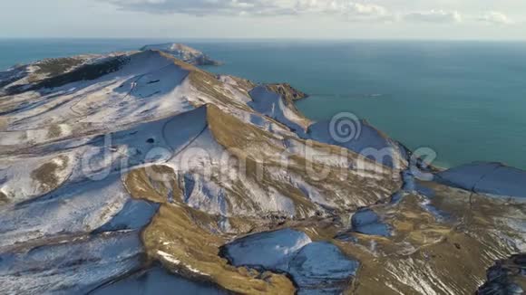 在多云的天空背景下鸟瞰雪山碧海射击冰岛海边的雪山视频的预览图