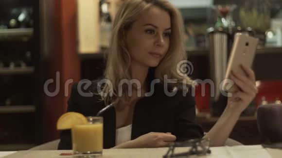 背景室内现代咖啡馆的年轻女子在手机上自拍视频的预览图