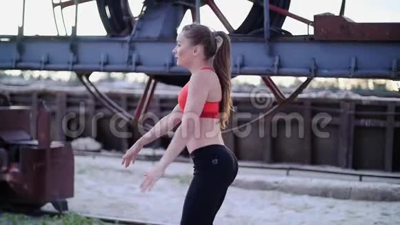 一位年轻的运动女性穿着红色上衣和黑色紧身裤进行各种力量练习训练她的肌肉关于视频的预览图