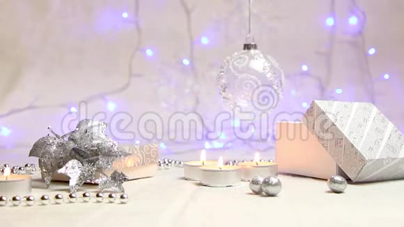 点燃蜡烛珠子一个挂着的新年舞会和一个银色礼品盒背景中有发光的蓝色灯笼视频的预览图