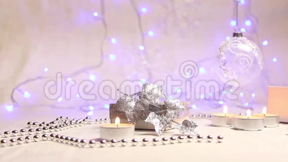点燃蜡烛珠子一个悬着的新年球和一个银色的礼品盒背景是明亮的蓝色灯笼一个视频的预览图