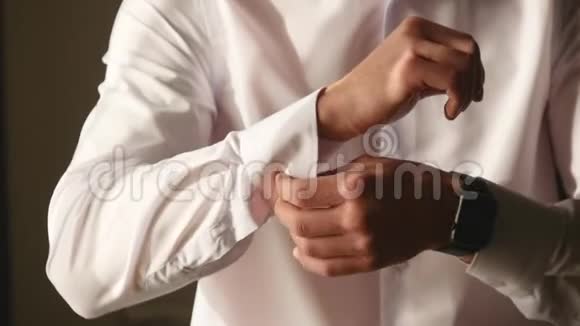 早上穿衣服的年轻男性手的特写镜头男人把袖口扣在衬衫上准备结婚视频的预览图