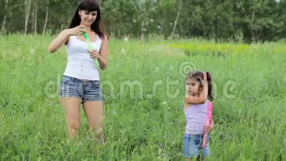 带着孩子在田里吹泡泡的女人有孩子的女人膨胀泡泡家庭价值观视频的预览图