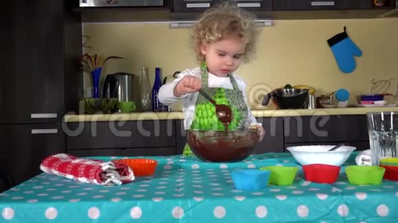 兴奋的小女孩在厨房里搅拌准备面团做蛋糕视频的预览图