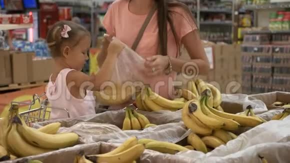 妈妈和小女儿在超市挑选水果的特写镜头视频的预览图