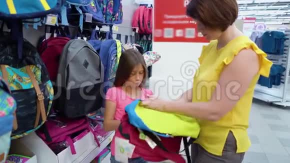在哈伯达舍市场白人母女在商店货架旁选择书包背包视频的预览图