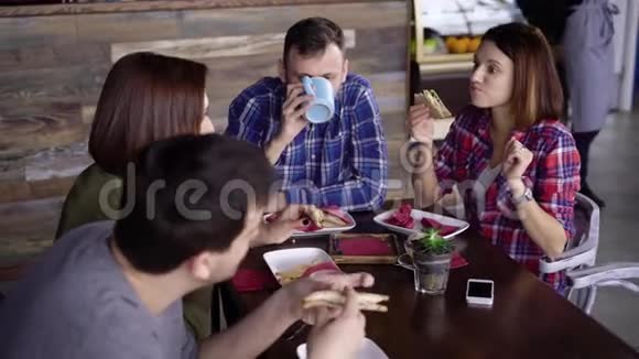 一群朋友坐在咖啡馆的桌子旁享受着他们的晚餐互相交谈两名男子和两名妇女视频的预览图