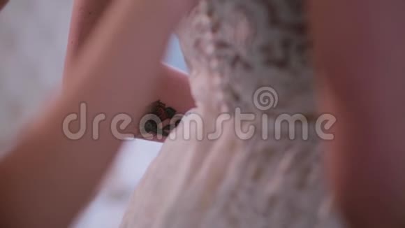伴娘帮着穿上婚纱在后面扣扣子早上准备有纹身的年轻新娘视频的预览图