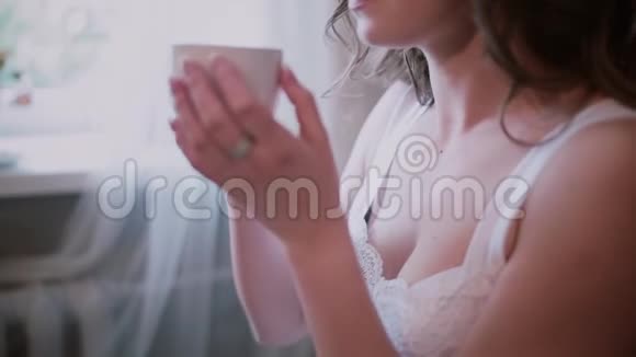 近景的女人穿着晚礼服坐在窗边喝咖啡漂亮的女孩在家吃早餐视频的预览图