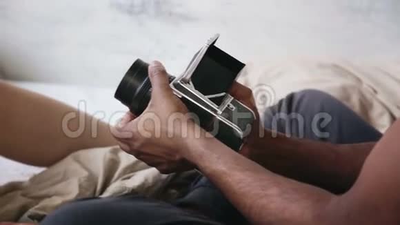 摄影师在旧动电影摄影机上拍照的特写镜头穿睡衣的年轻女人对男人摆姿势视频的预览图