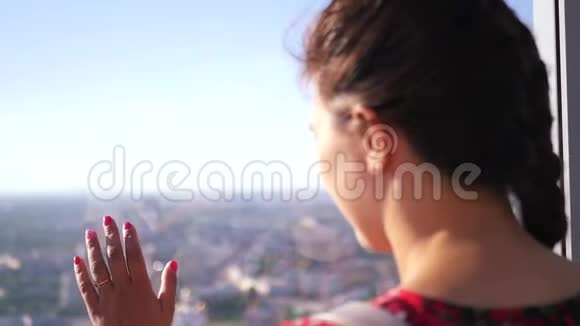 一个年轻的女孩看着窗外鸟瞰看着城市看着远处下面的动作高清高清视频的预览图