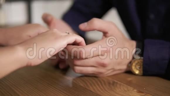 一对年轻夫妇手牵手坐在木桌旁的特写镜头相亲相爱的情侣视频的预览图
