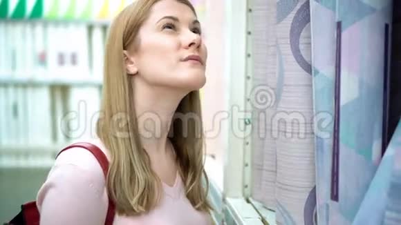 美丽迷人的年轻女子在商店的货架上挑选墙纸消费主义概念视频的预览图
