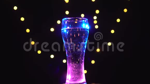 一杯淡蓝色的水在旋转粉色蓝色鸡尾酒酒吧概念视频的预览图