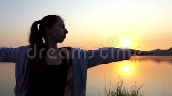 两位年轻女子在日落的美丽湖岸做瑜伽运动视频的预览图