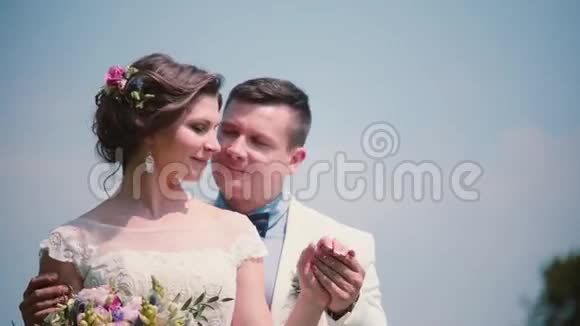 快乐的新郎轻轻地握住他漂亮的新娘的手看着它一对站在战场上的夫妇婚礼的装饰品视频的预览图